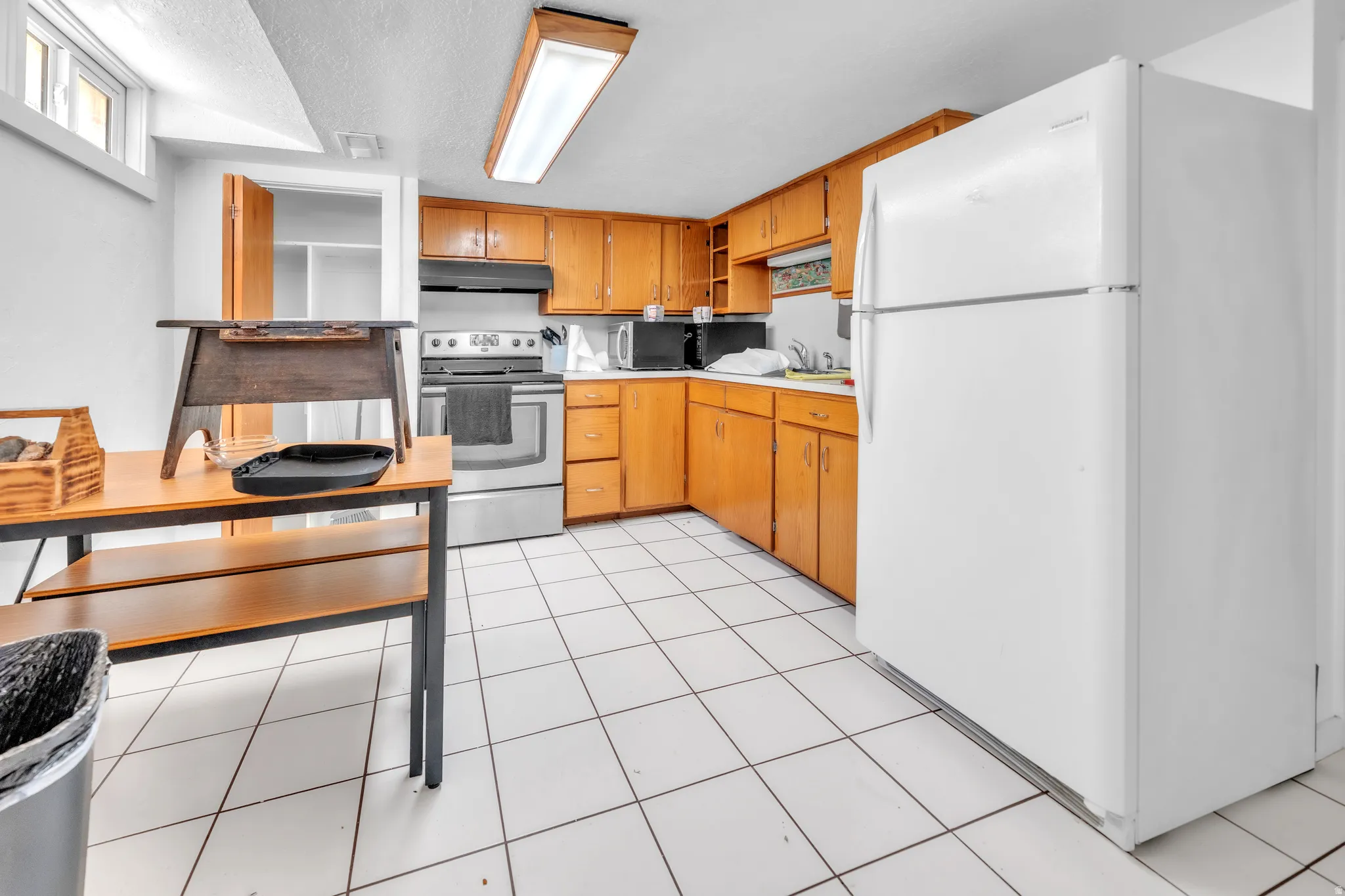 Kitchen area featuring white tile flooring, wood-finish cabinetry, and stainless steel range