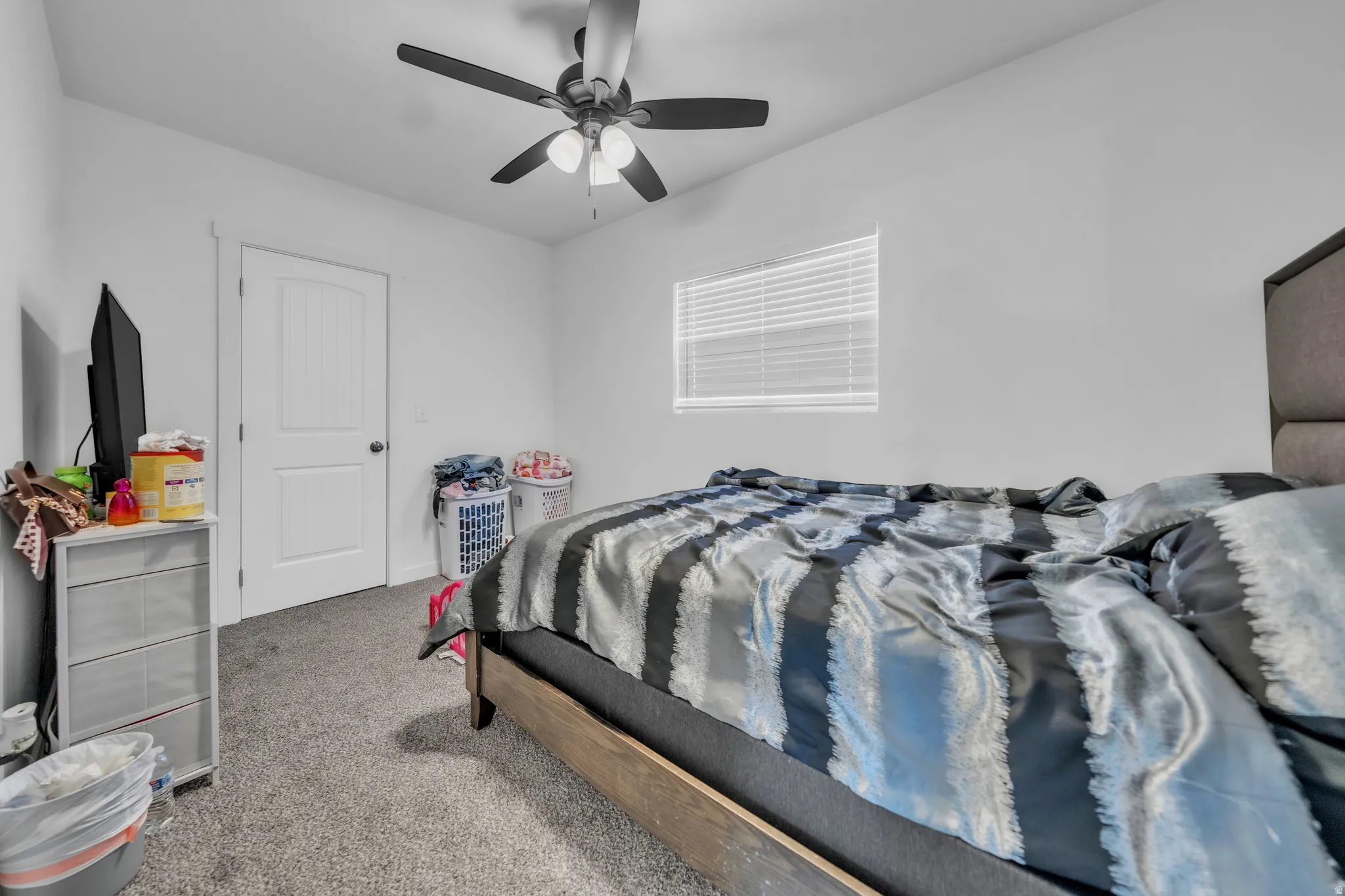Carpeted flooring, white walls, and a ceiling fan with integrated lighting