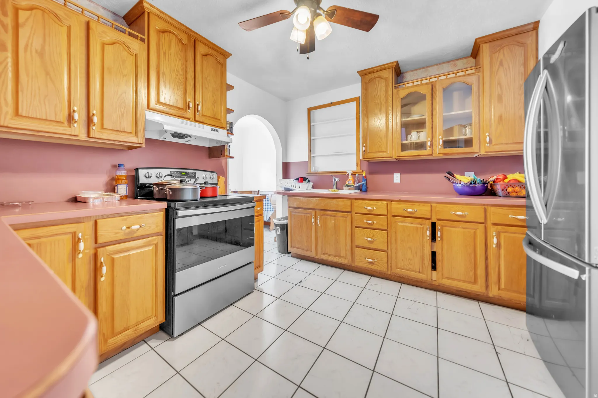 Kitchen featuring extensive wood cabinetry, solid surface countertops, stainless steel range, and tile flooring