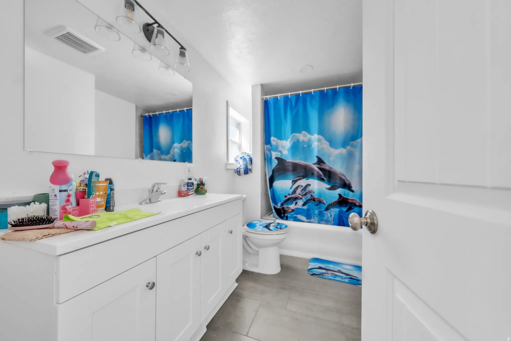 White vanity with chrome fixtures, large wall-mounted mirror, track lighting, and a white paneled door