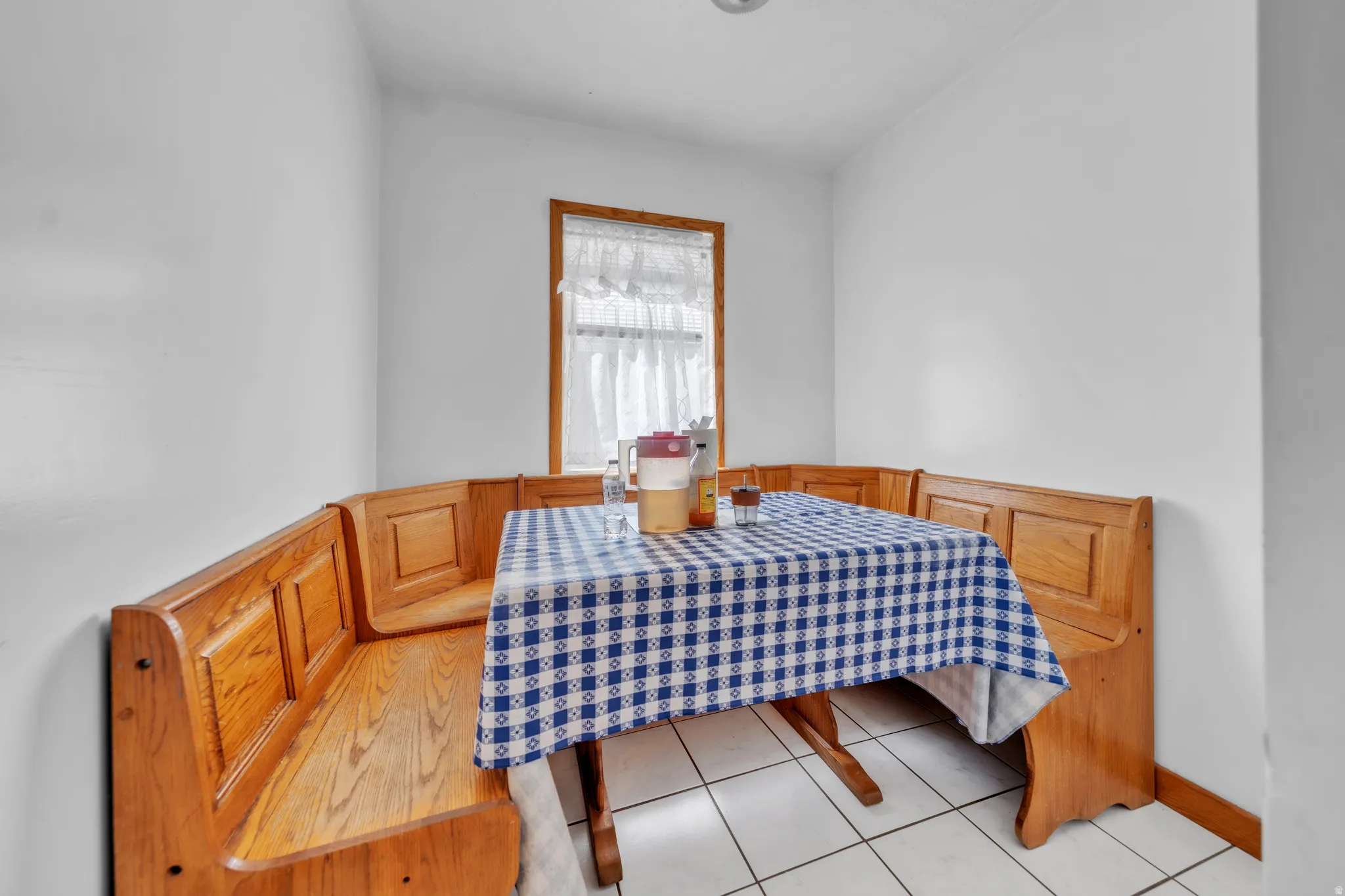 Built-in corner bench seating with wood-finish paneling, wood-frame window, and tiled flooring