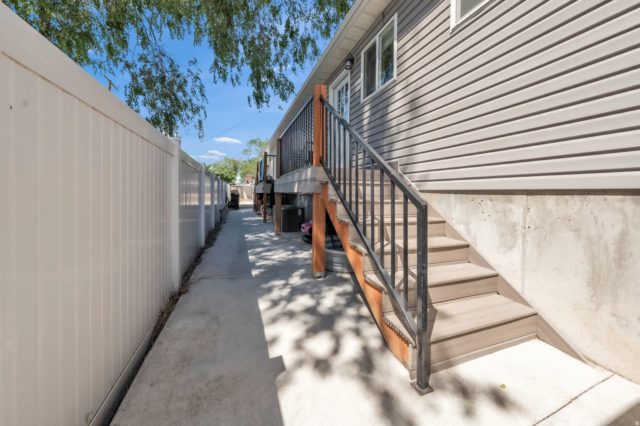 Exterior featuring light-toned horizontal siding, concrete foundation, and a full-height privacy fence