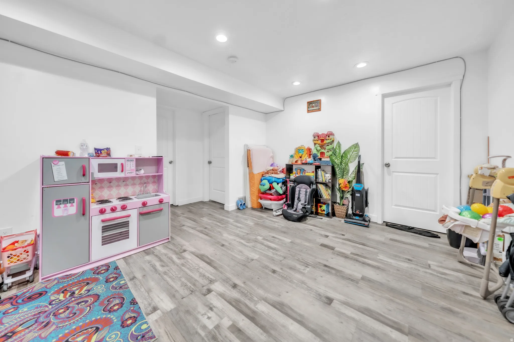Recessed lighting, wood-finish flooring, white walls, and two white doors