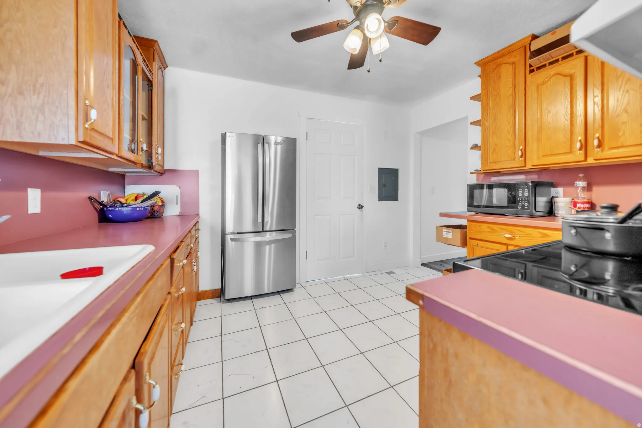 Kitchen featuring wood cabinetry, white tile flooring, and a stainless steel refrigerator