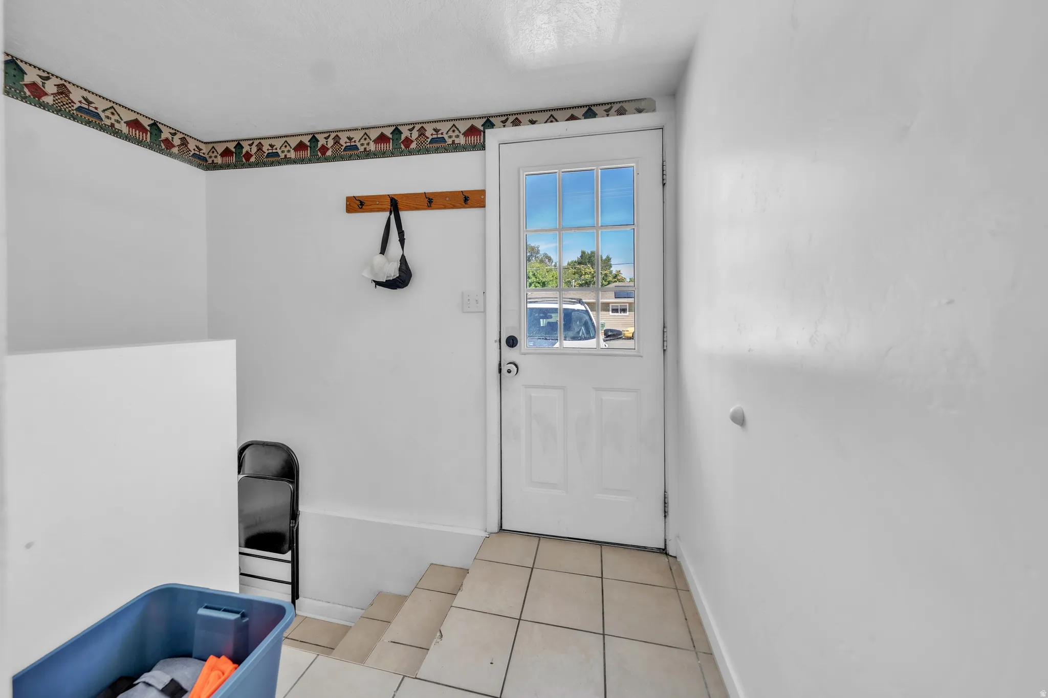 Entryway with tile flooring, a glass-paned door, and a built-in wooden coat rack