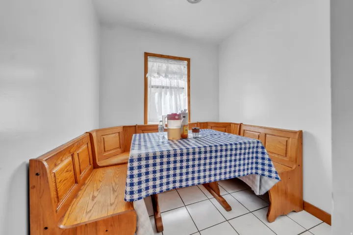 Built-in corner bench seating with wood-finish paneling, wood-frame window, and tiled flooring