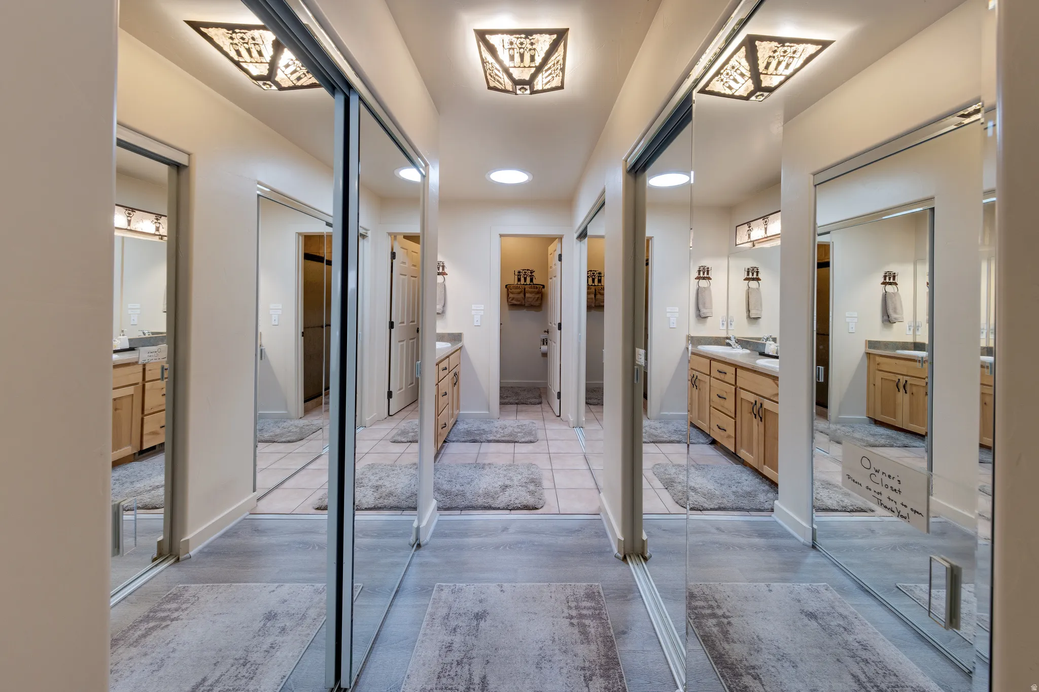 Hallway featuring mirrored sliding closet doors, wood-finish flooring, recessed lighting, and decorative ceiling light fixtures