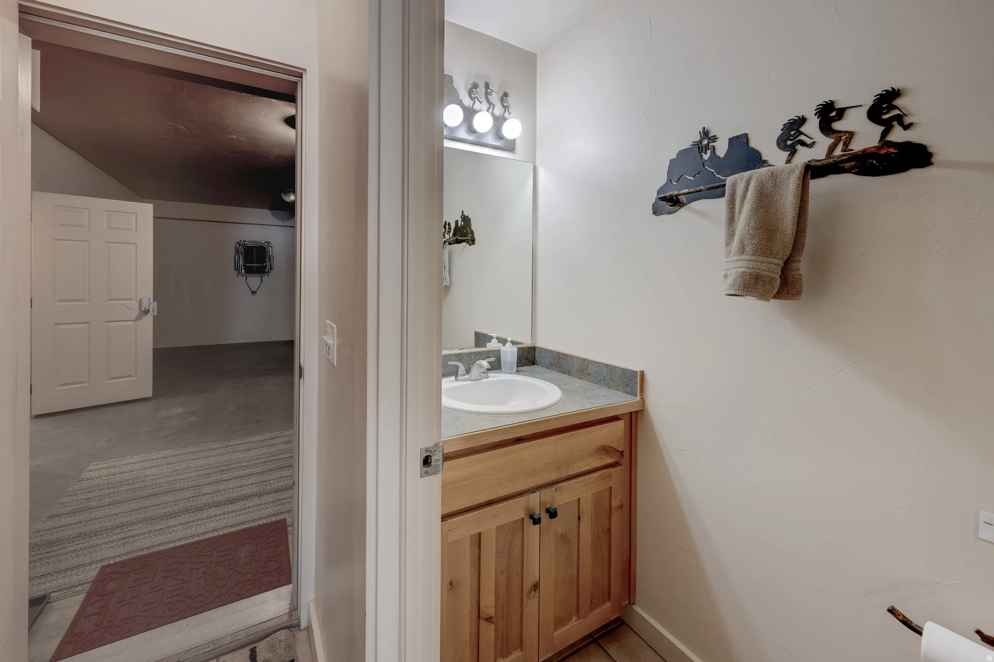 Wood-finish flooring, single vanity with a laminate countertop, and a round undermount sink