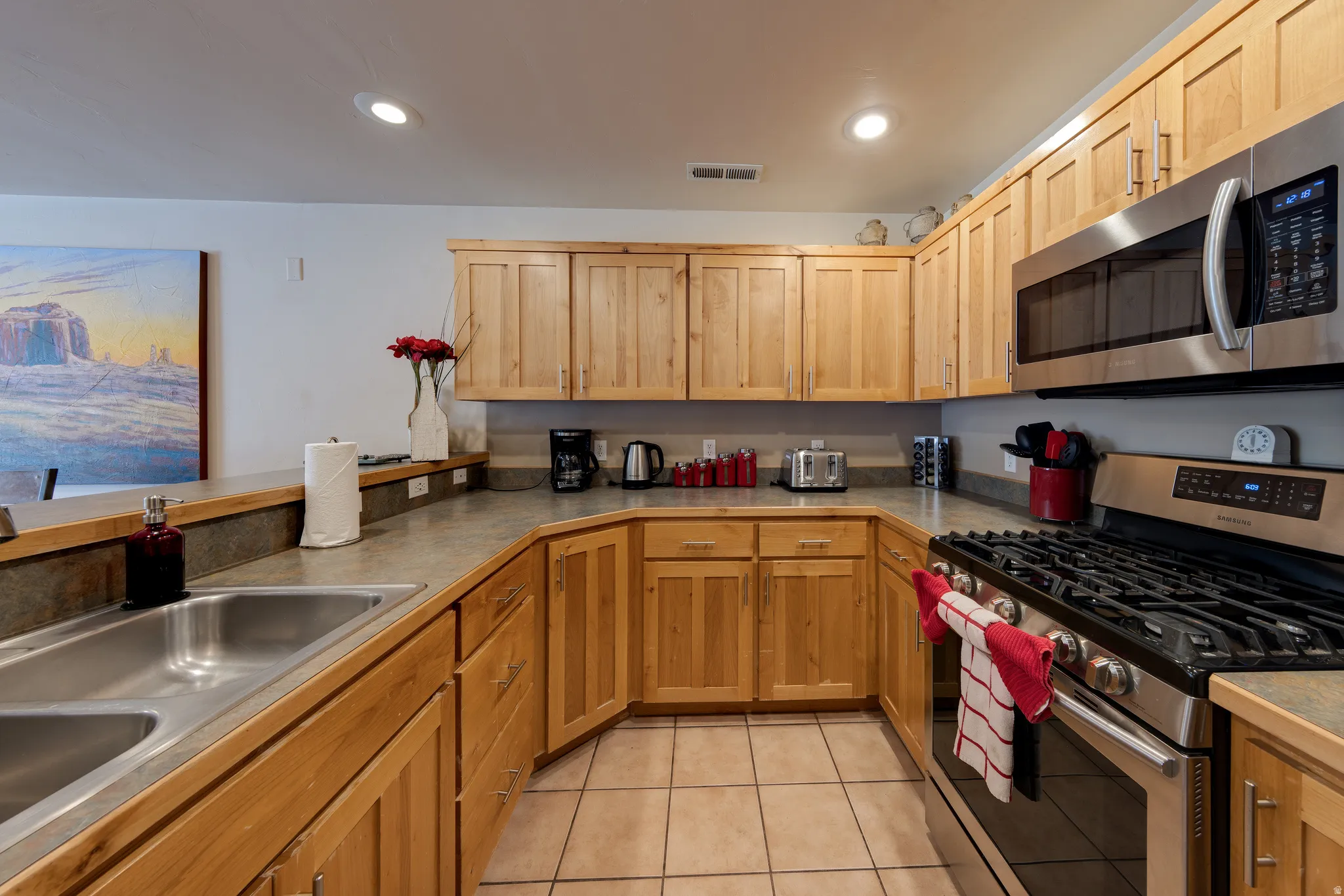 U-shaped kitchen with wood cabinetry, stainless steel appliances, recessed lighting, and tile flooring