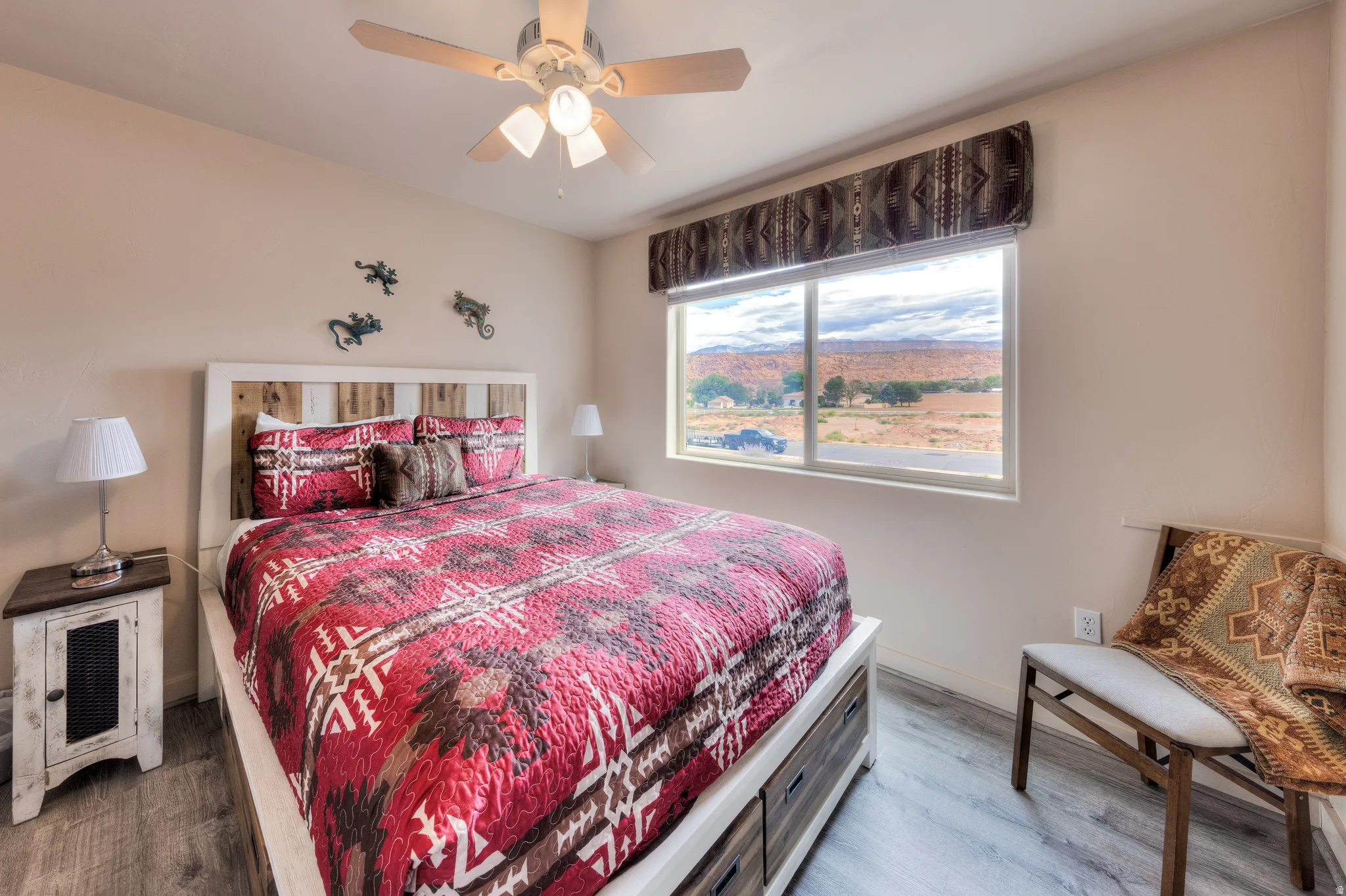 Bedroom featuring a rustic-style headboard, wood-finish flooring, and a ceiling fan with integrated lighting