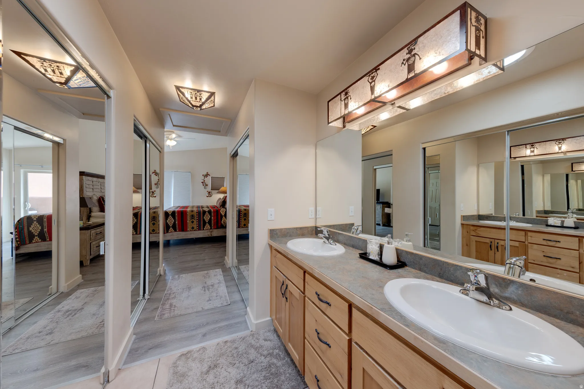 Dual vanity with integrated sinks, light wood-finish cabinetry, and a large mirror