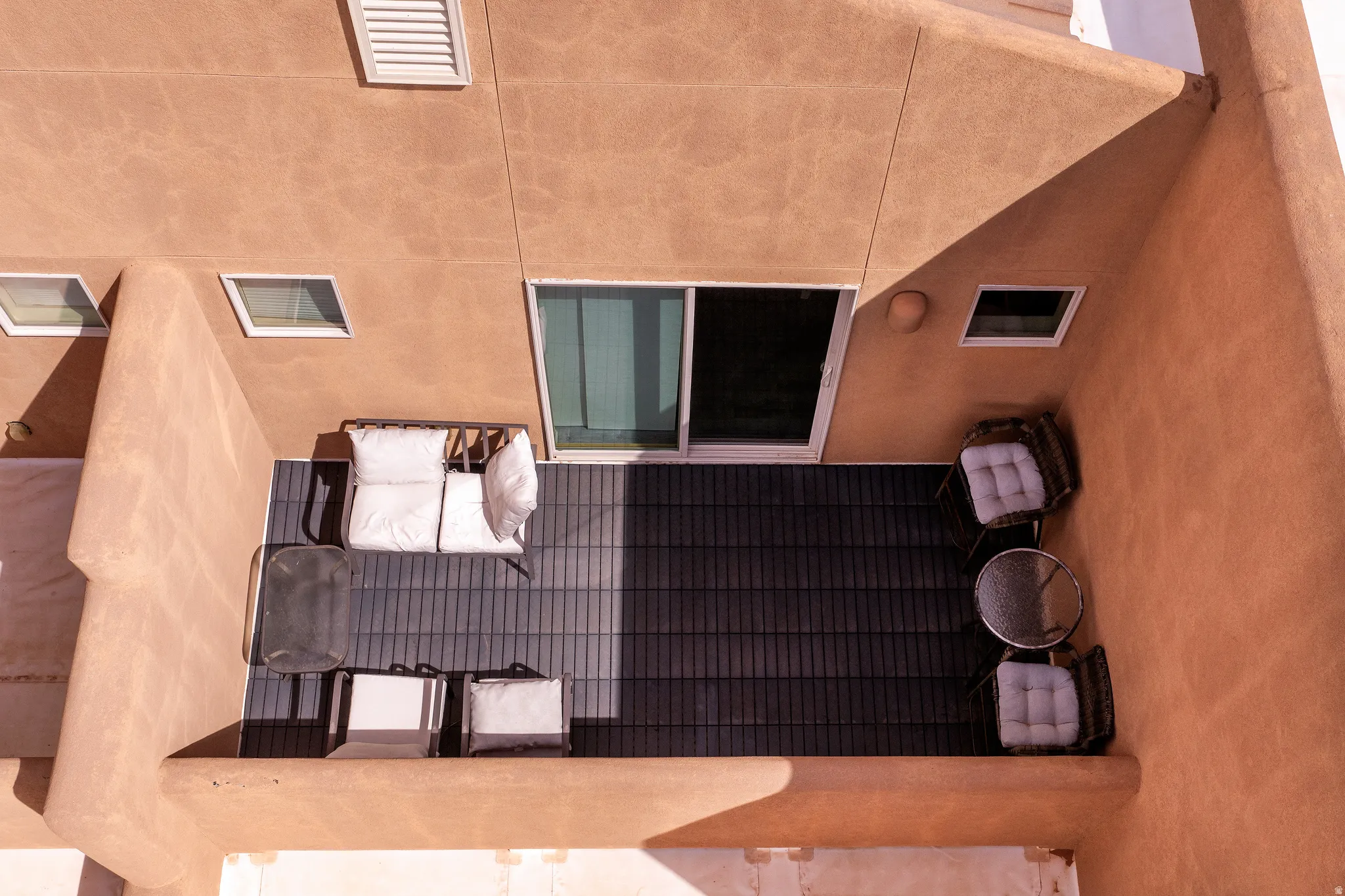 Private exterior patio space featuring dark plank flooring, a stucco exterior finish, and a sliding glass door