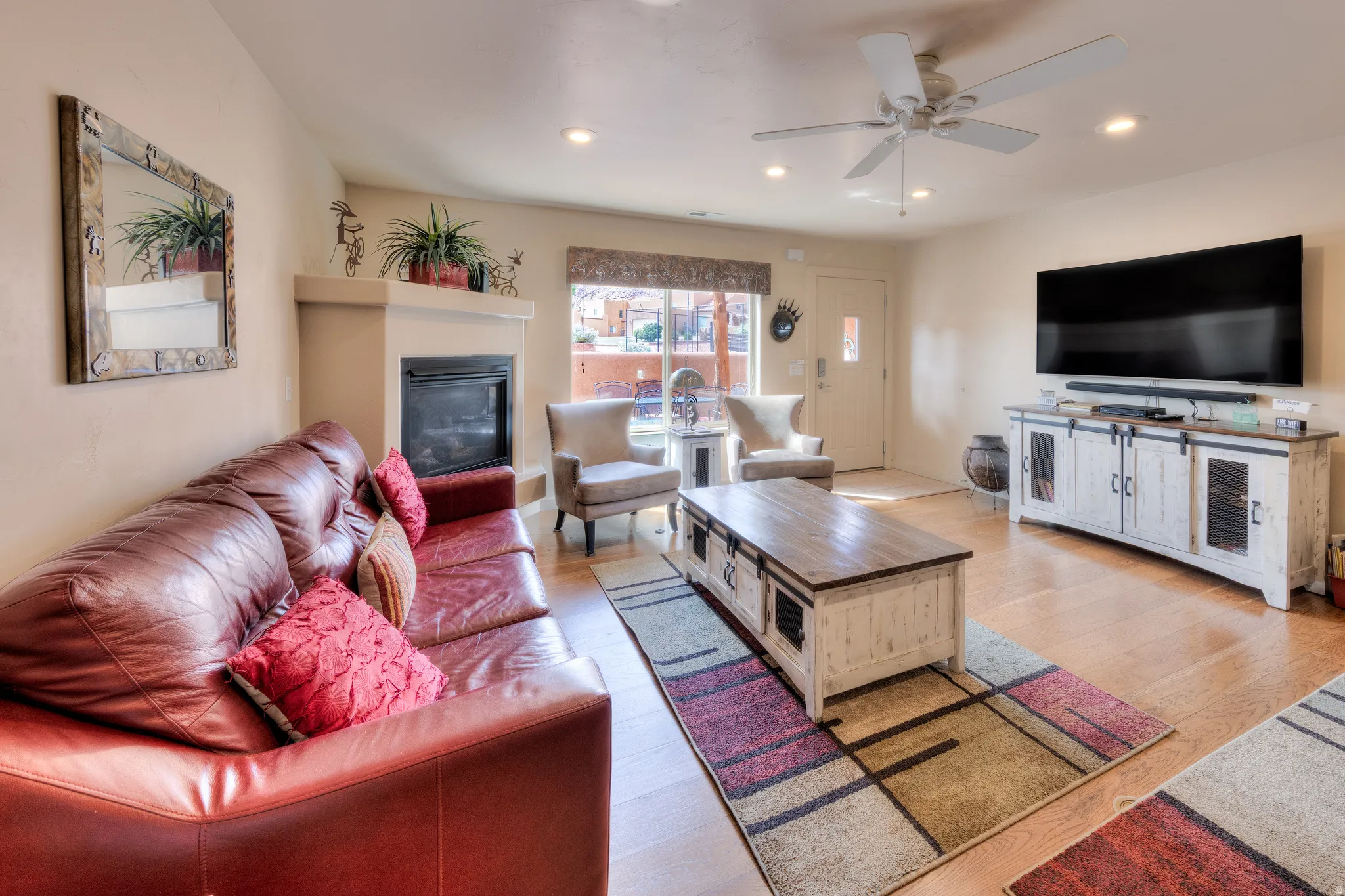 Light wood-finish flooring, recessed lighting, ceiling fan, fireplace with mantel, and built-in entry door