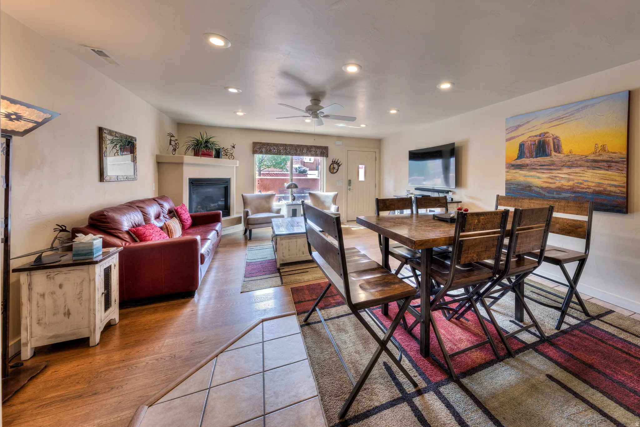 Corner fireplace with mantel, wood-finish flooring, recessed lighting, ceiling fan, and tiled entry