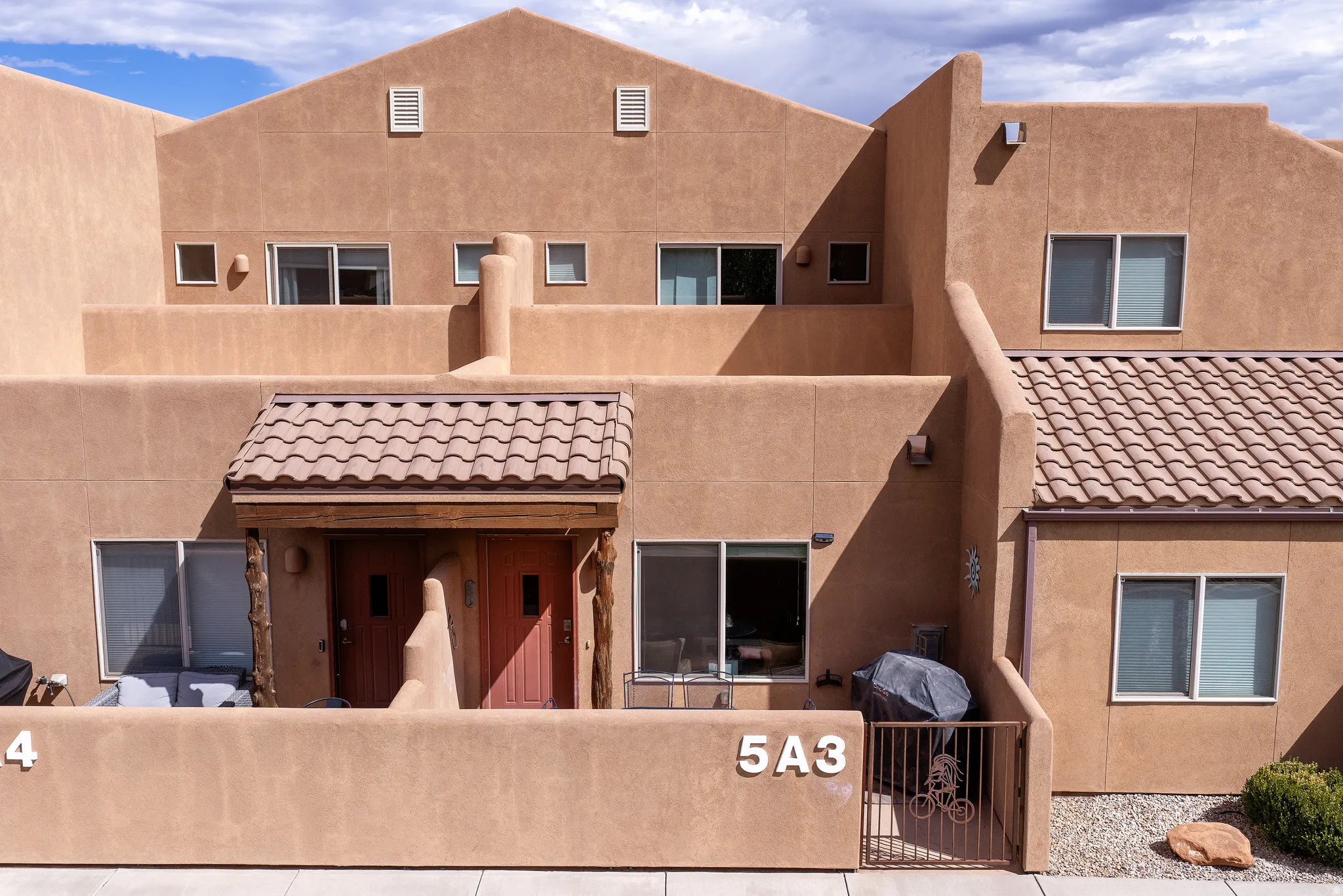 Stucco exterior with multiple windows, a private patio, and a covered entry with a tiled roof