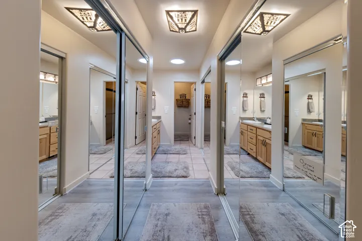 Hallway featuring mirrored sliding closet doors, wood-finish flooring, recessed lighting, and decorative ceiling light fixtures