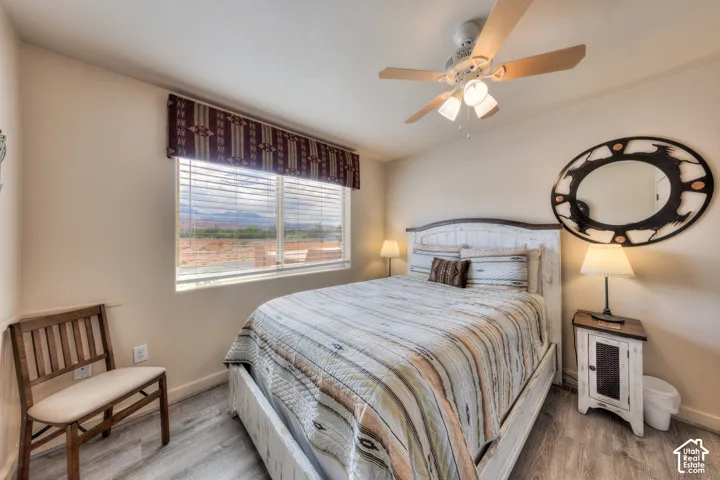 Wood-finish flooring, ceiling fan with integrated lighting, and a window with horizontal blinds