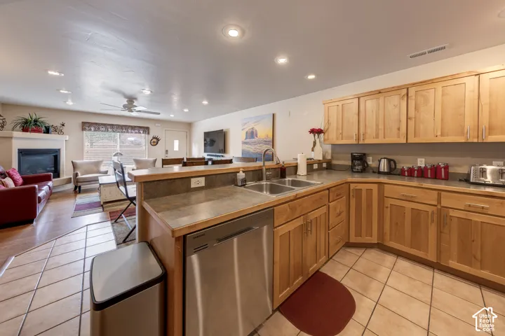 Kitchen featuring natural wood cabinetry, stainless steel dishwasher, double basin sink, and tile flooring