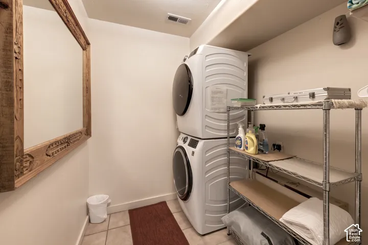 Tile flooring, stacked laundry appliances, and built-in shelving