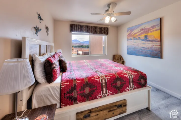 Built-in bed frame with integrated storage drawers, window with mountain scenery, ceiling fan with integrated lighting, wood-finish flooring, and neutral wall paint