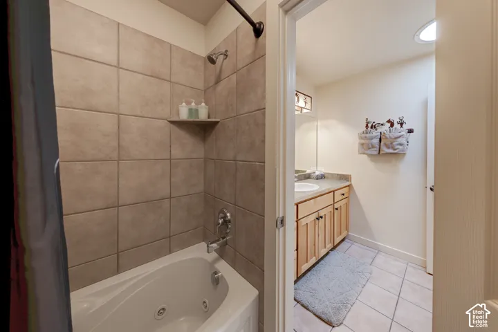 Jetted tub with tile surround, wood cabinetry with a countertop, recessed lighting, and a circular skylight