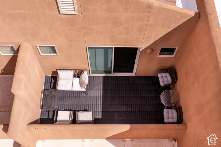 Private exterior patio space featuring dark plank flooring, a stucco exterior finish, and a sliding glass door