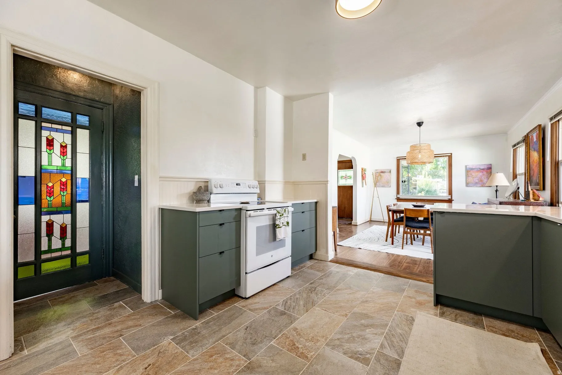 Stained glass entry door, tile flooring, updated cabinetry, white countertops, and white appliances