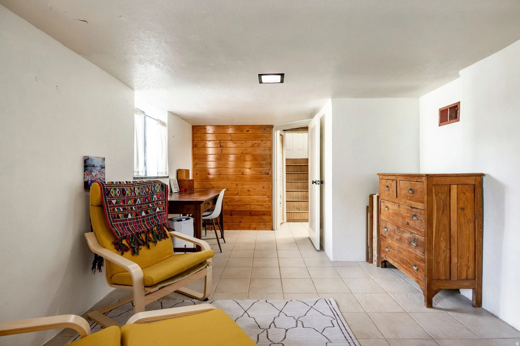 Tile flooring paired with white walls, wood panel accent wall, and recessed ceiling lighting