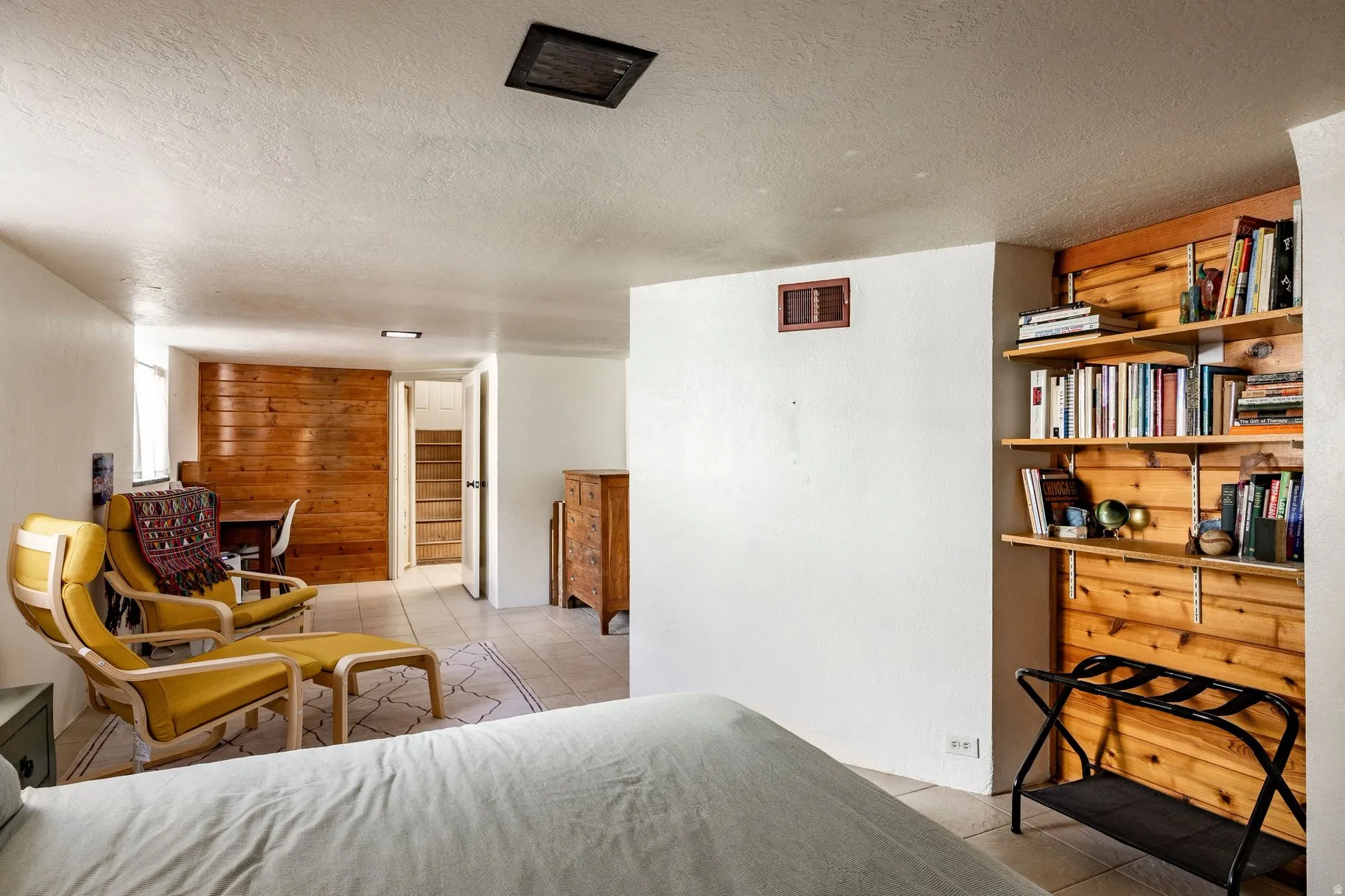 Tile flooring, wood panel accent wall, built-in shelving, white painted walls, and a visible doorway to a stairwell