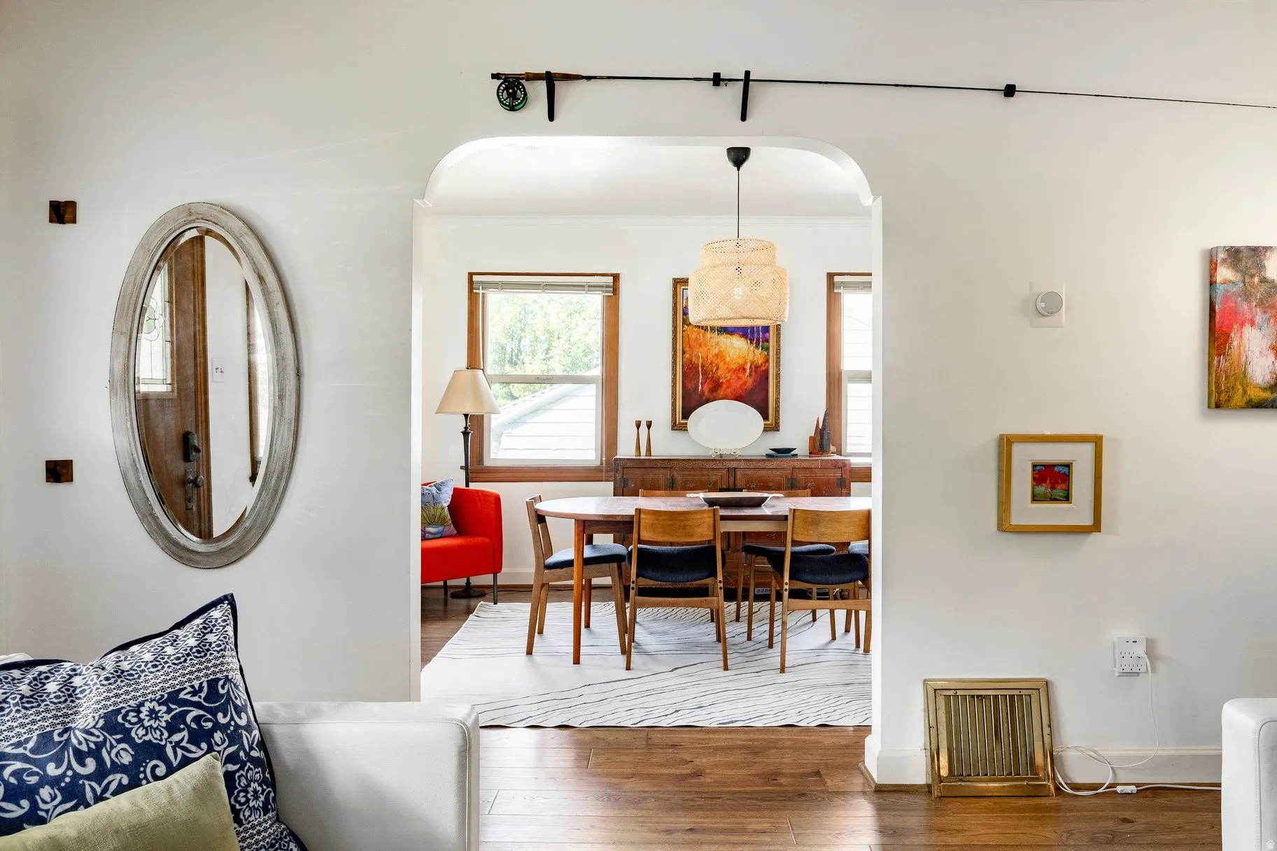 Arched doorway providing access to a dining area with wood-finish flooring and a central pendant light fixture