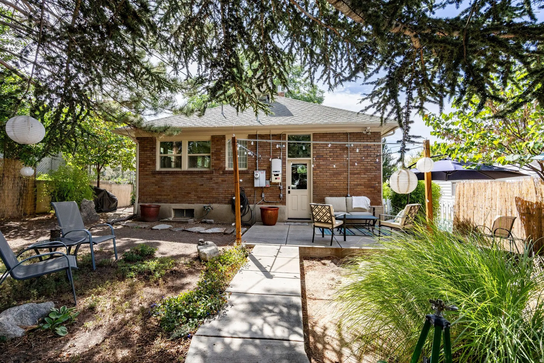 Brick exterior with a paved patio, mature trees, and a privacy fence