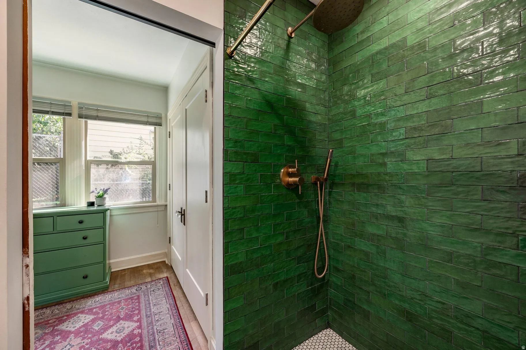 Shower featuring green subway tile, brushed gold shower fixtures, and a white hexagonal tile floor