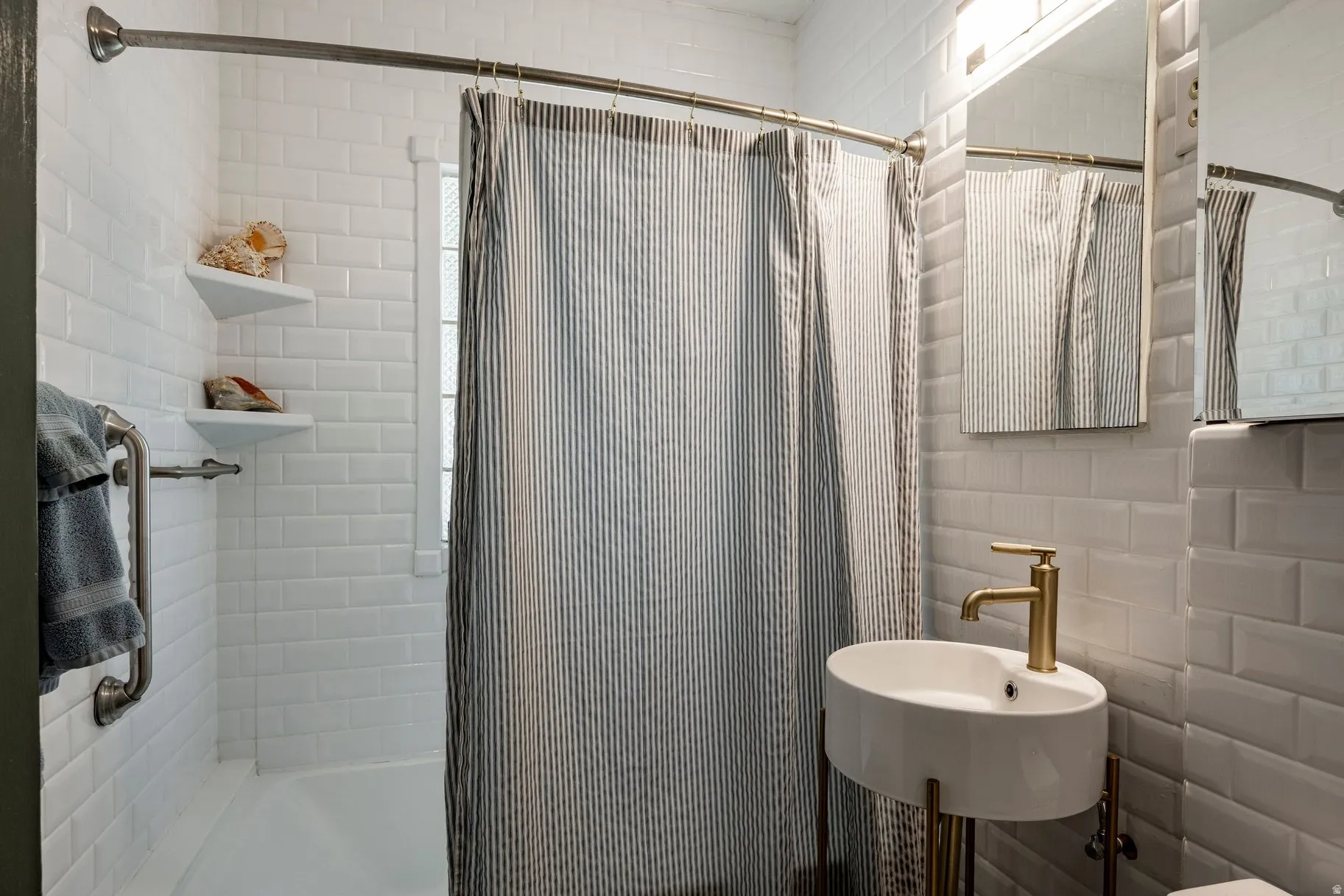 White subway tile surround, built-in bathtub, and corner shelving