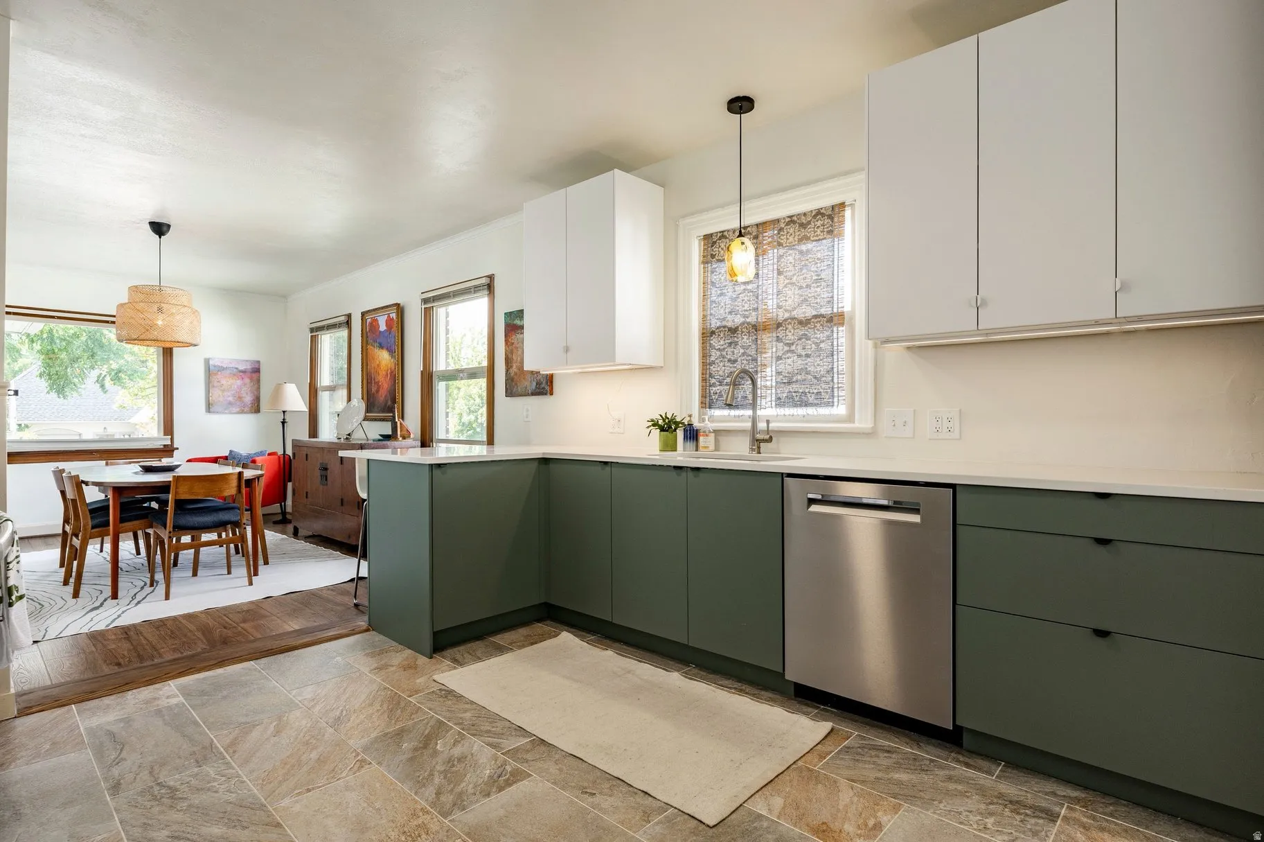 Kitchen featuring white upper cabinetry, dark green lower cabinetry, stainless steel dishwasher, and light-toned countertops