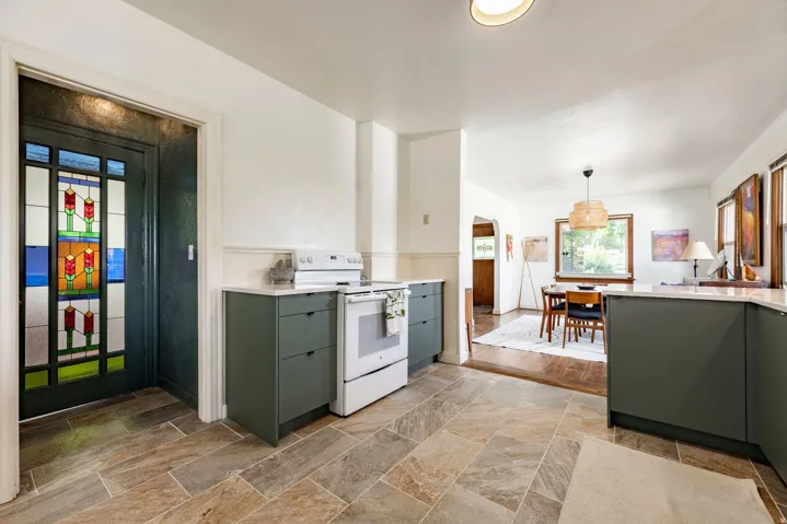 Stained glass entry door, tile flooring, updated cabinetry, white countertops, and white appliances