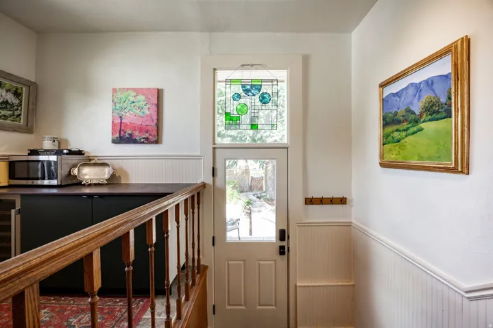 White paneled door with stained glass transom window, wood railing, and wainscoting