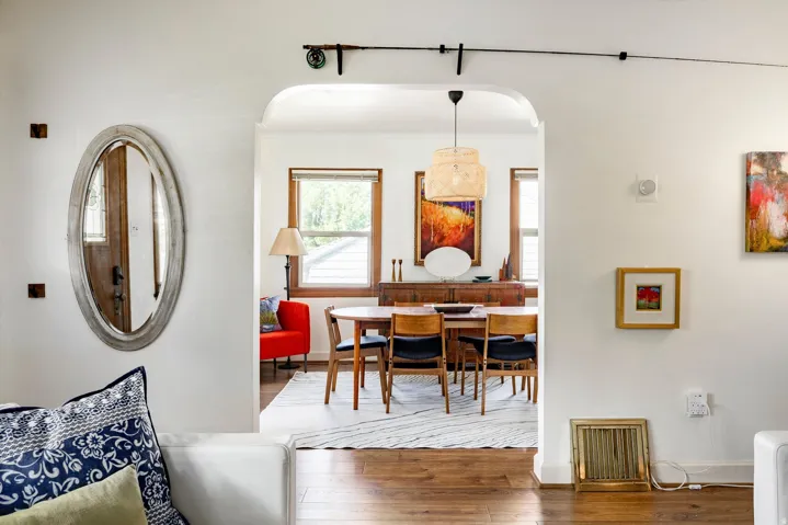 Arched doorway providing access to a dining area with wood-finish flooring and a central pendant light fixture