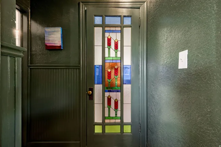 Entryway featuring a stained-glass door with floral motifs, beadboard paneling, and a brass doorknob