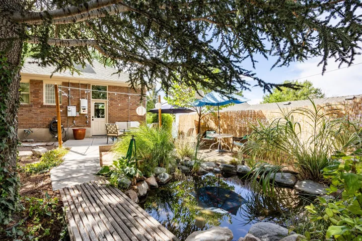 Brick exterior featuring a patio, garden pond with a wooden bridge, and established trees