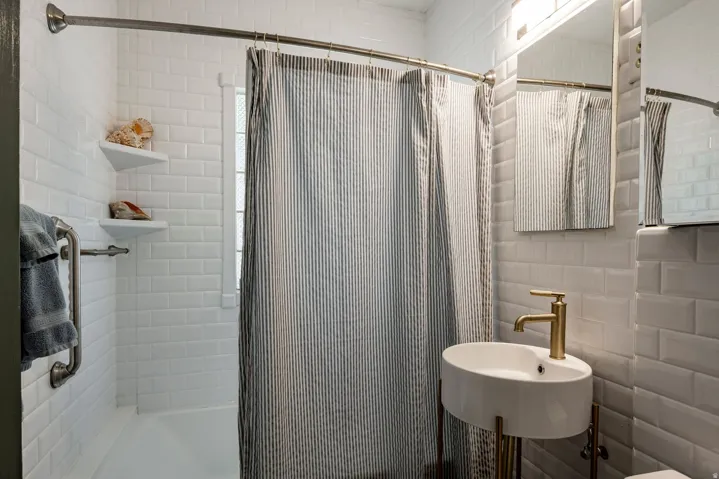 White subway tile surround, built-in bathtub, and corner shelving