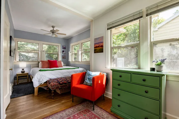 Wood-finish flooring, multiple windows, ceiling fan, and painted walls