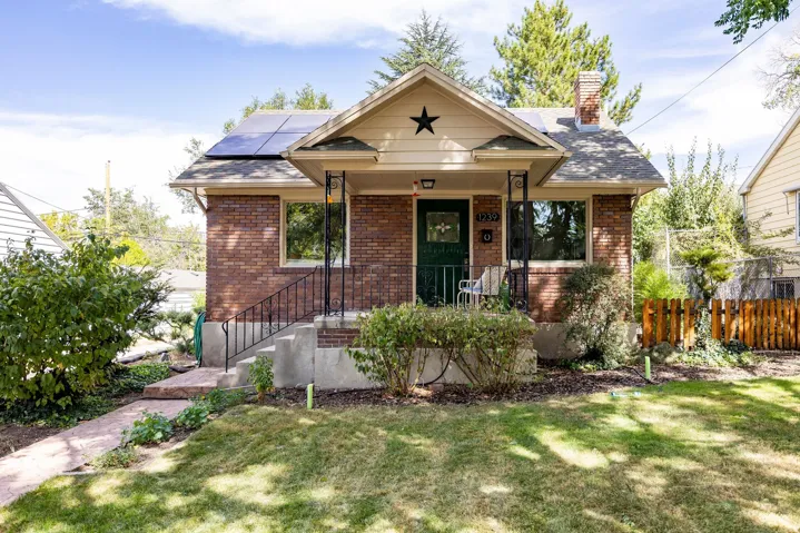 Brick exterior with a covered front porch featuring wrought iron railings and columns