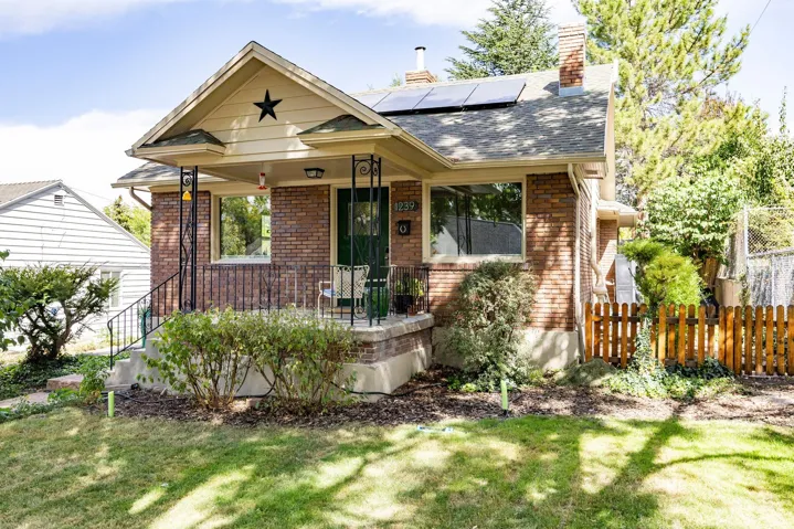 Brick exterior with a covered front porch, decorative metal railings, and an asphalt shingle roof