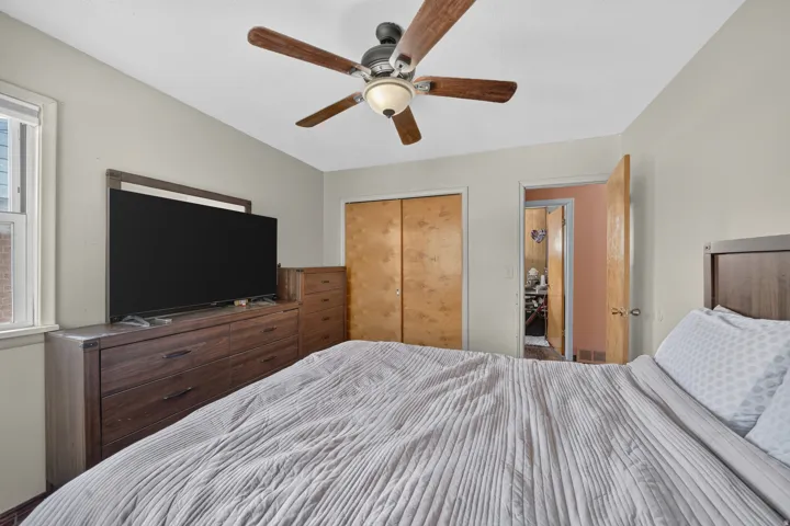 Ceiling fan with wood-finish blades, window with natural light, and closet with wood-finish bi-fold doors