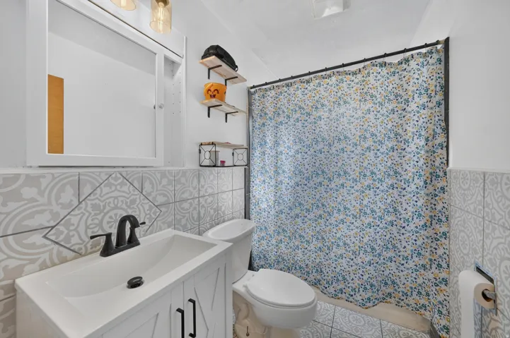 Vanity with integrated sink, matte black faucet, and patterned tile surround