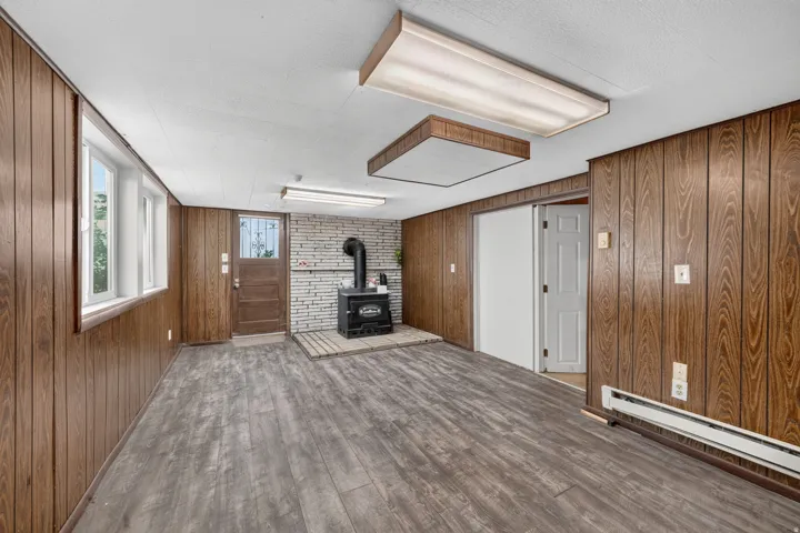 Wood-finish wall paneling, multi-pane windows, and a wood-burning stove with a stone surround