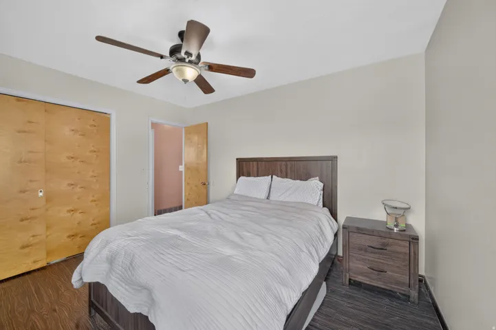 Wood-finish flooring, light-toned walls, and a ceiling fan with integrated lighting