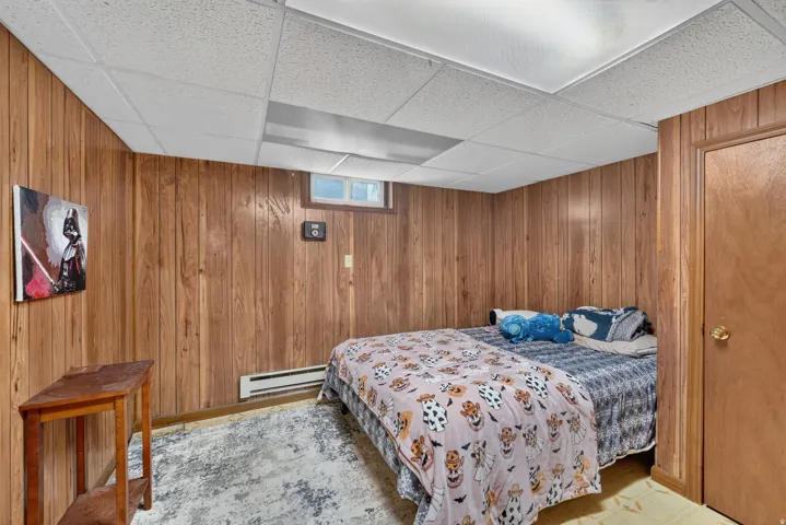 Wood-paneled wall, drop ceiling with recessed lighting, small window, and wood-finish door