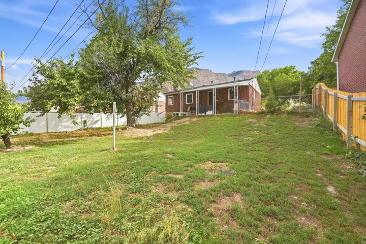 Expansive green space featuring a wood fence, mature trees, and a brick exterior structure