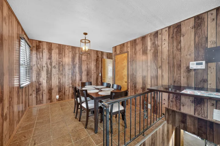 Wood-finish paneling, tiled flooring, built-in staircase railing, and a window with blinds